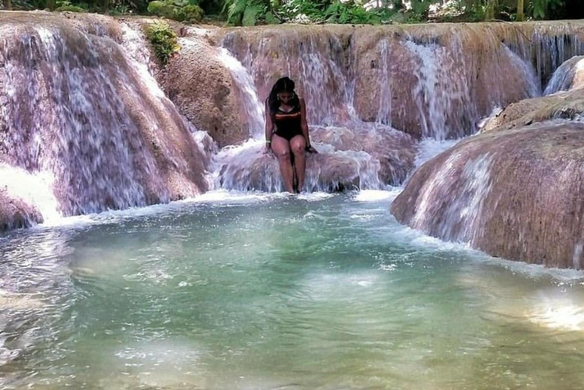 a woman is standing in a waterfall