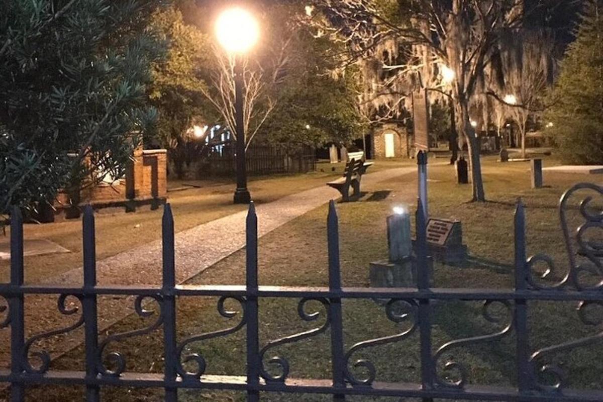a park at night with a fence and a bench