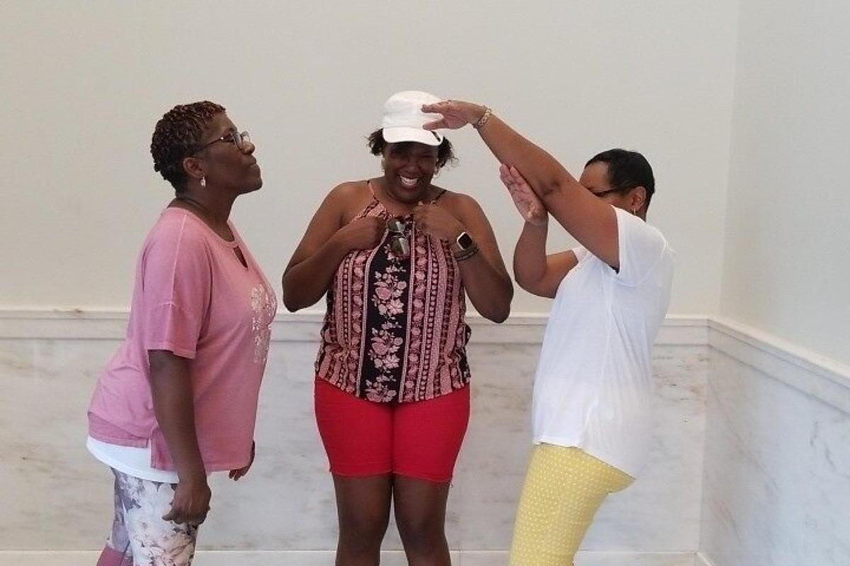 a group of people standing around a woman wearing a hat