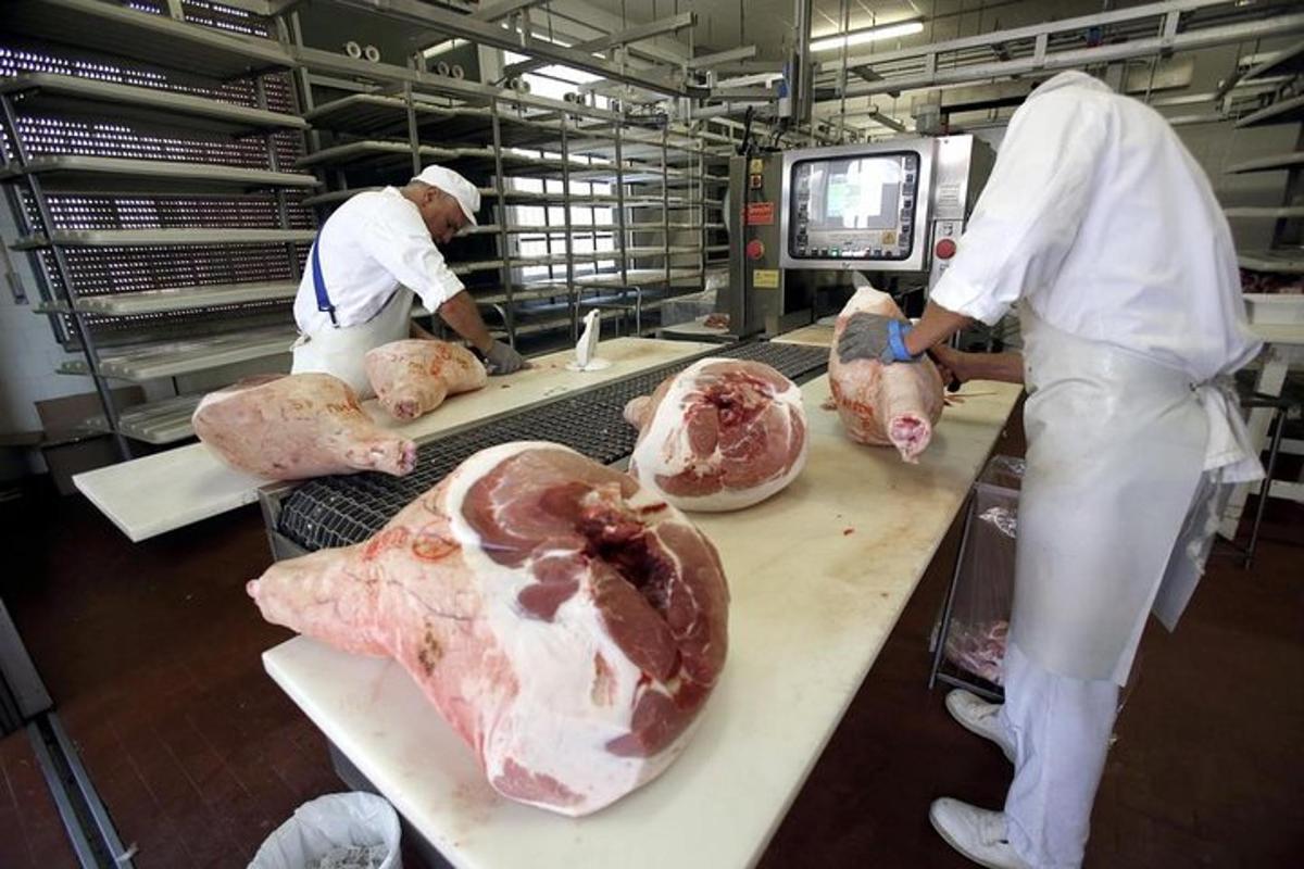 a group of people in a kitchen preparing meat
