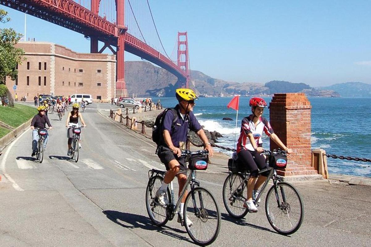 Skupina ljudi, ki vozijo kolesa pred mostom Golden Gate