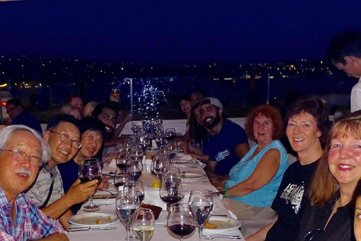 un gruppo di persone sedute a un lungo tavolo con bicchieri di vino