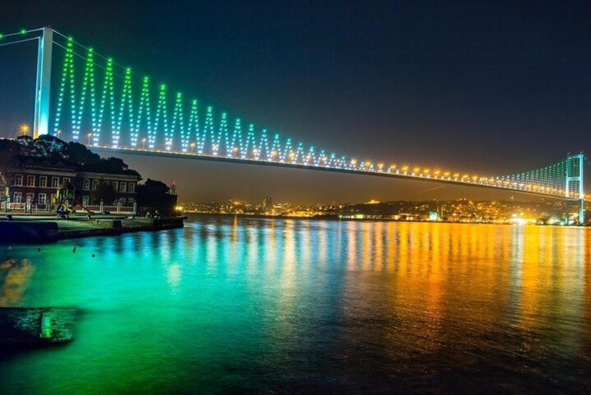 un ponte con luci verdi sopra un fiume di notte