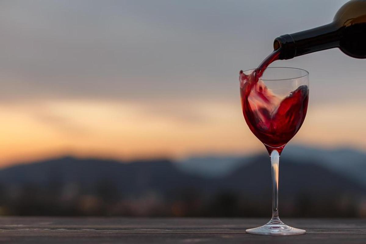 eine Person gießt Rotwein in ein Weinglas