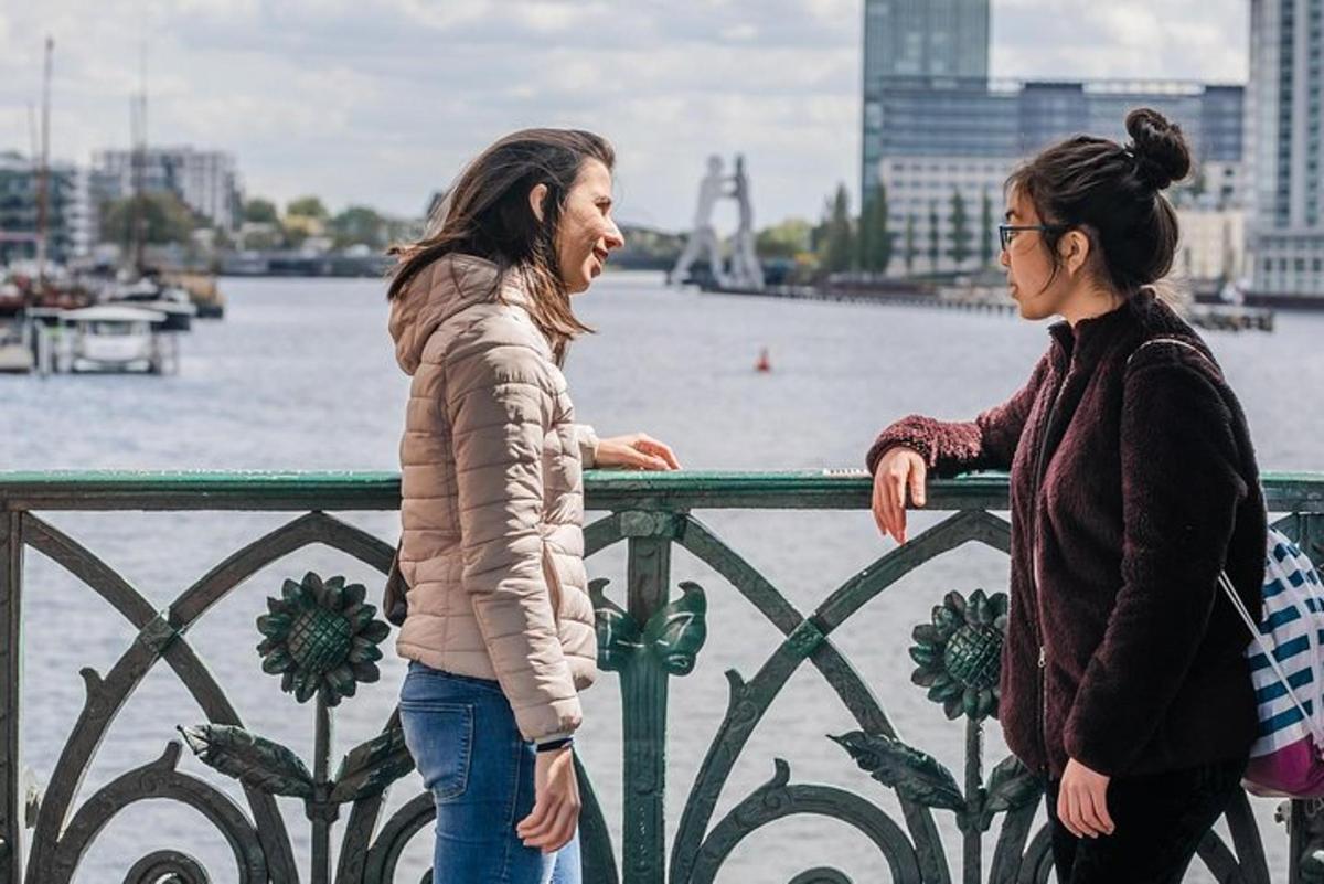 Dos mujeres de pie junto a una valla cerca del agua.