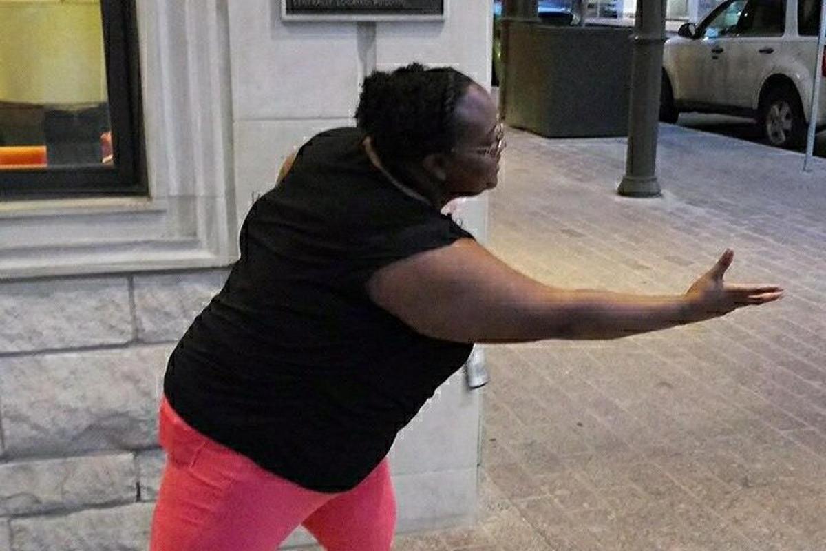 a woman standing on a sidewalk with her arm outstretched