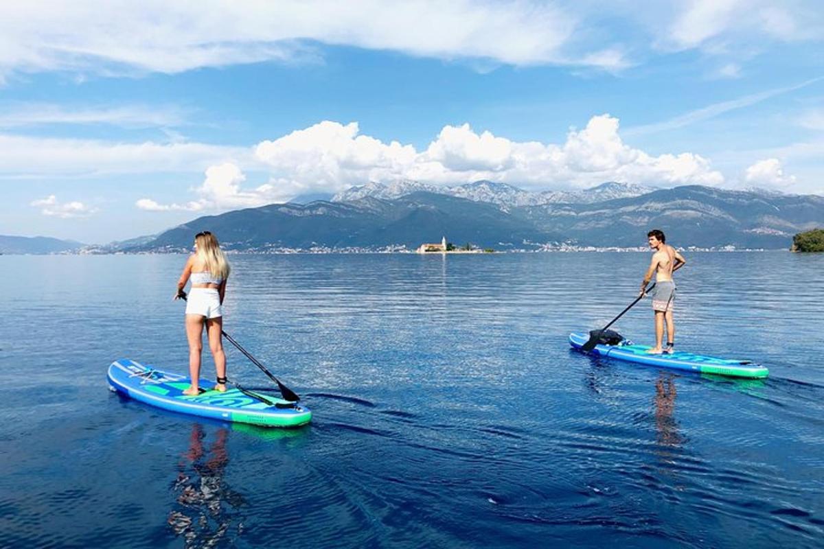 dva lidé stojí na paddleboardech ve vodě