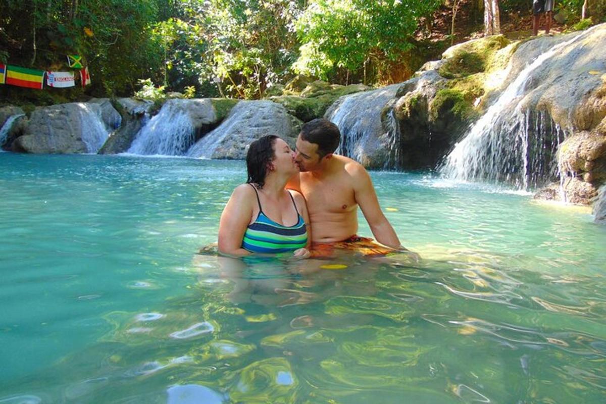 un uomo e una donna seduti nell'acqua di fronte a una cascata