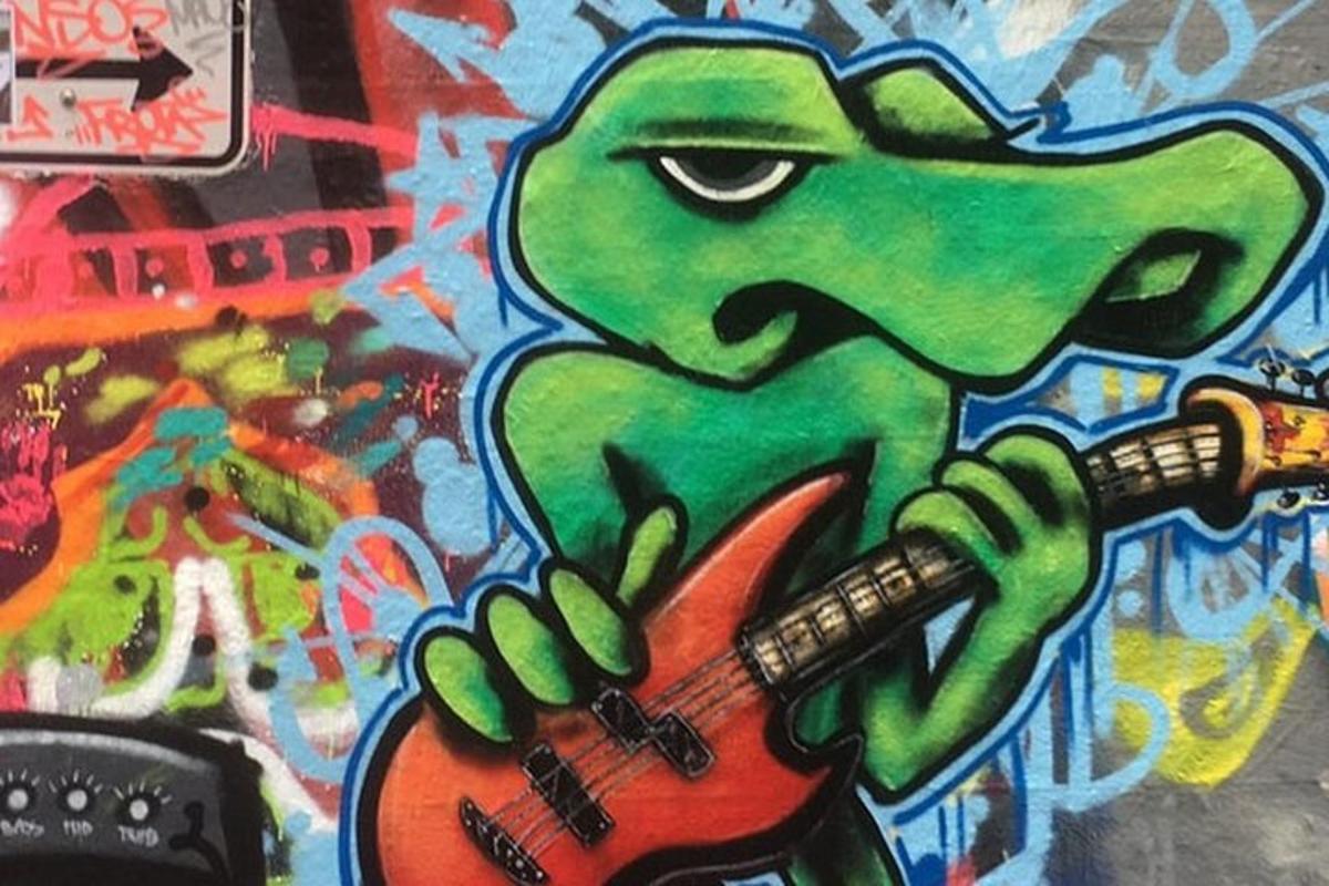 een schilderij van een hagedis die gitaar speelt op een muur