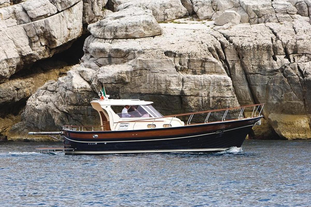 a boat in the water next to a rock wall