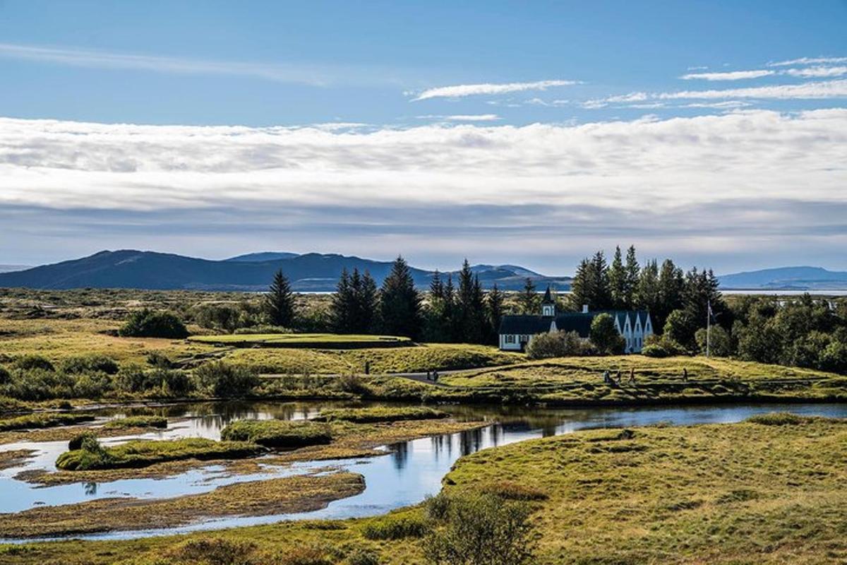 una vista di un campo con un fiume e montagne