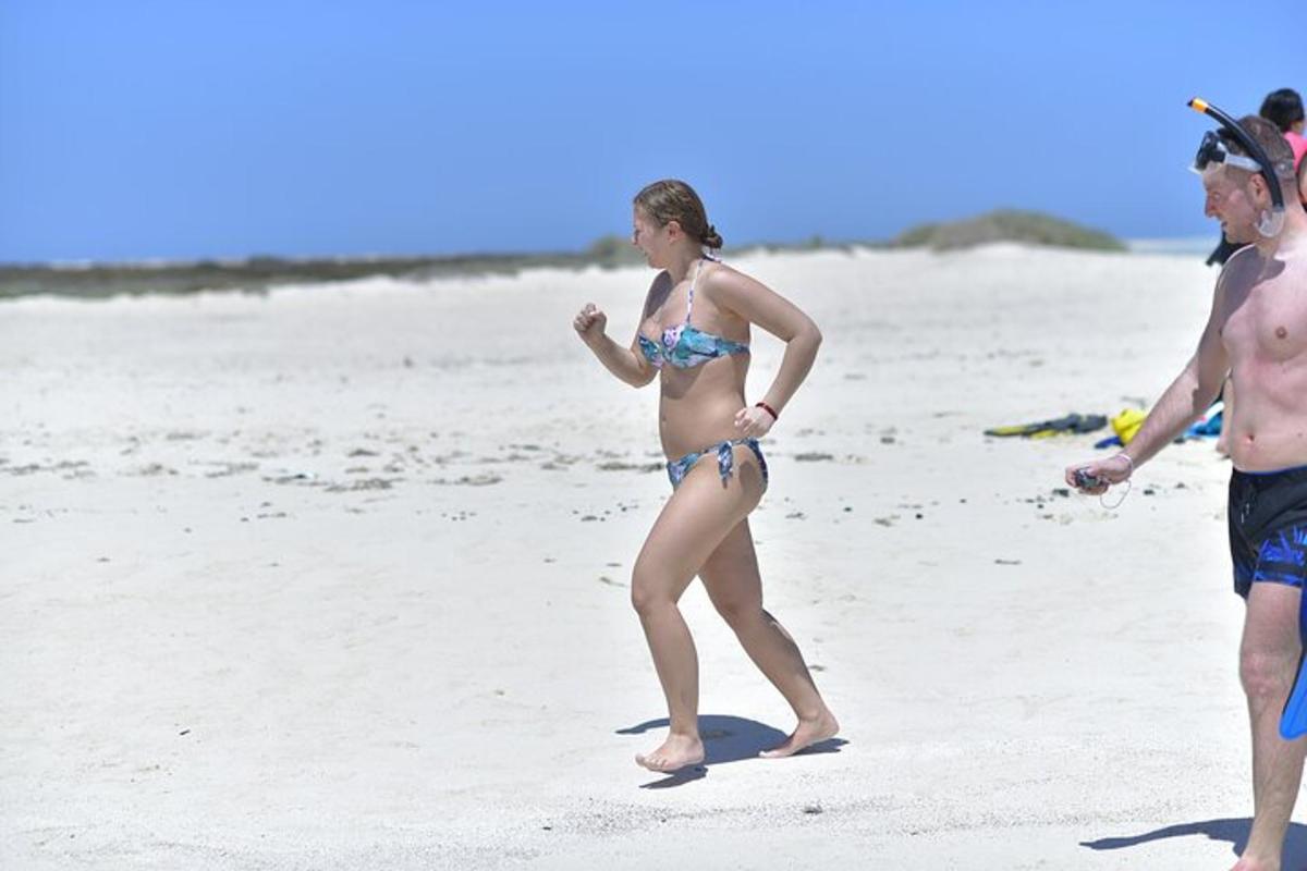 en kvinne i bikini som går på stranden