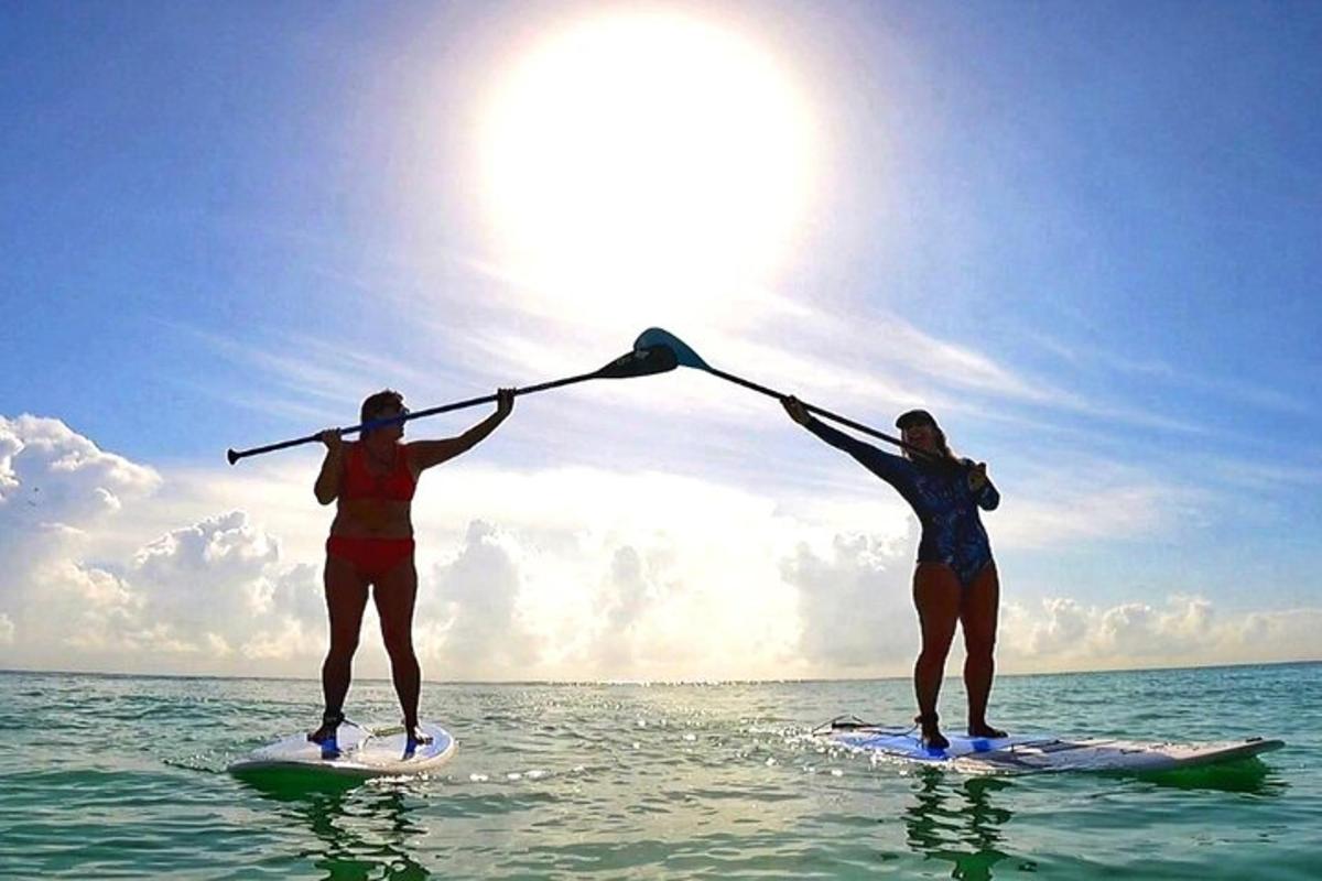 Dos mujeres en tablas de surf en el océano sosteniendo sus remos
