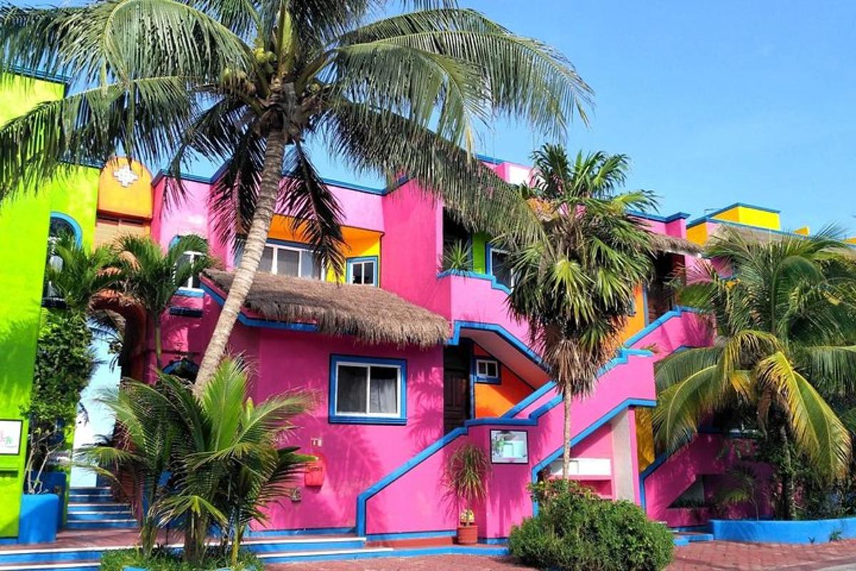 un edificio rosa con palme di fronte