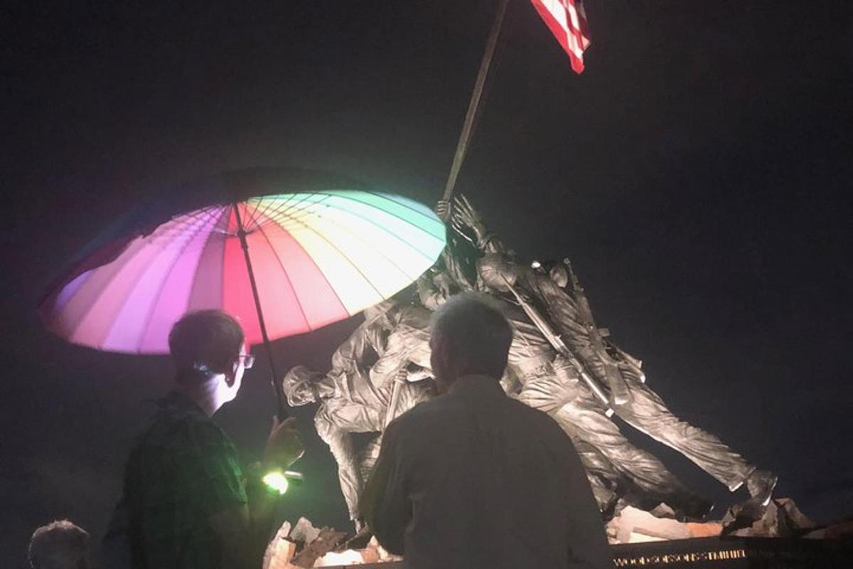 a couple of people standing under a colorful umbrella