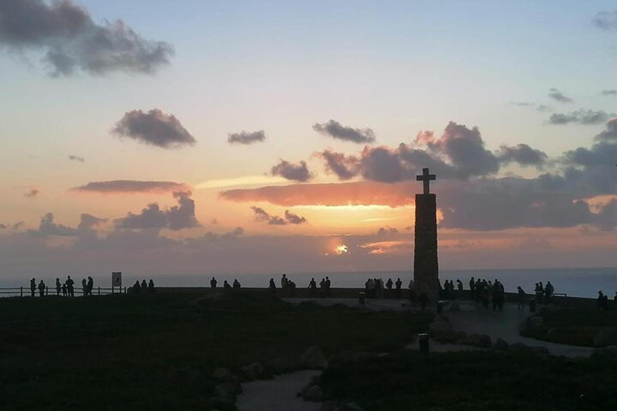 a group of people standing around a cross at sunset