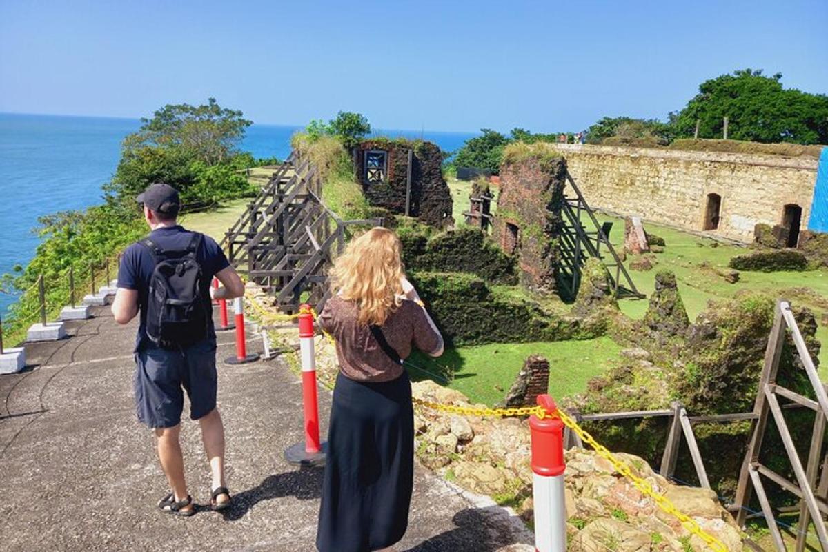 a man and a woman standing on a road near the ocean