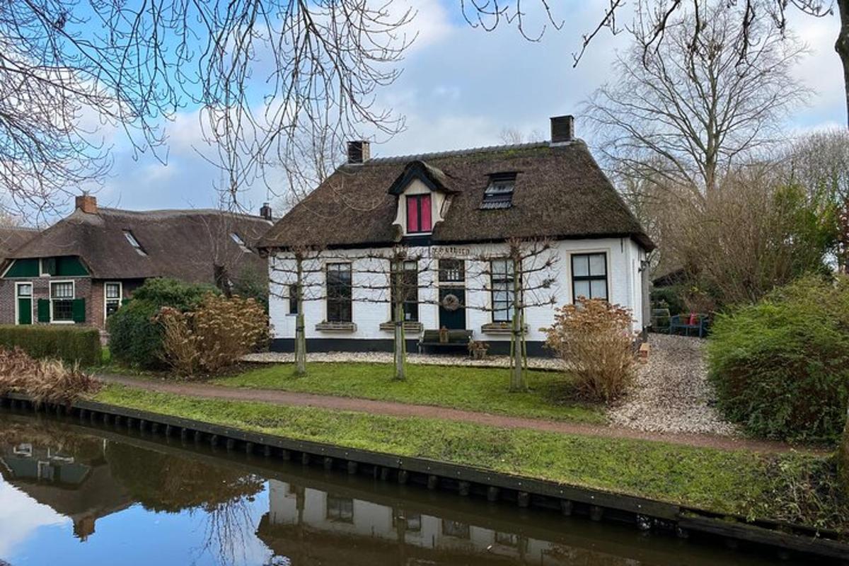 a white house with a red window next to a river