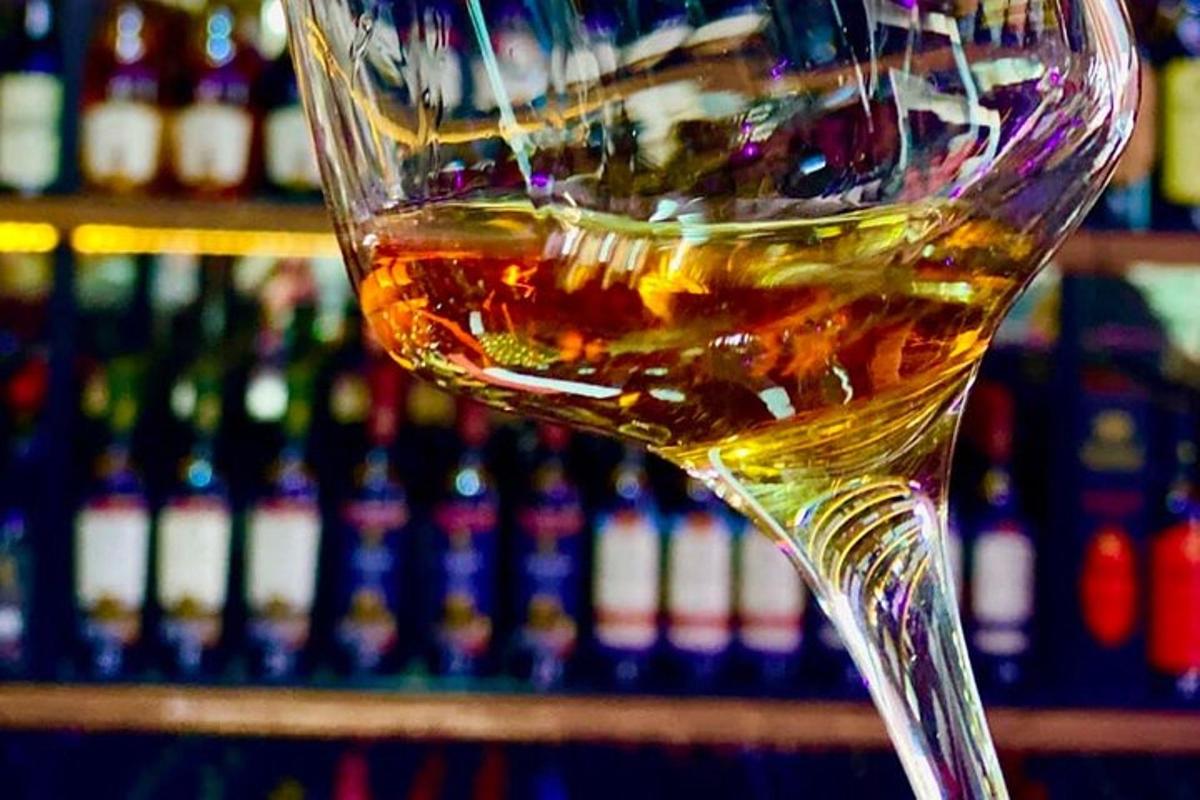 ein Glas Whisky vor einem Flaschenregal