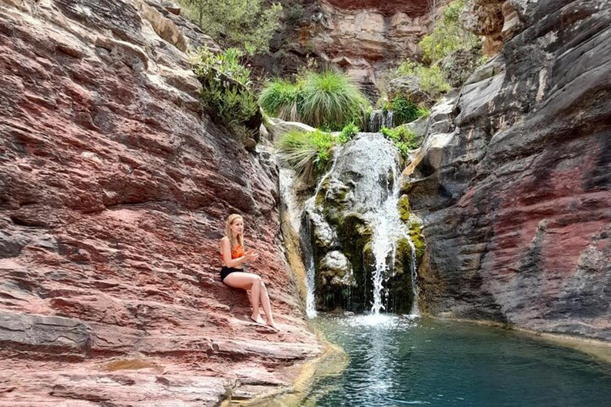 una dona asseguda en una roca davant d'una cascada