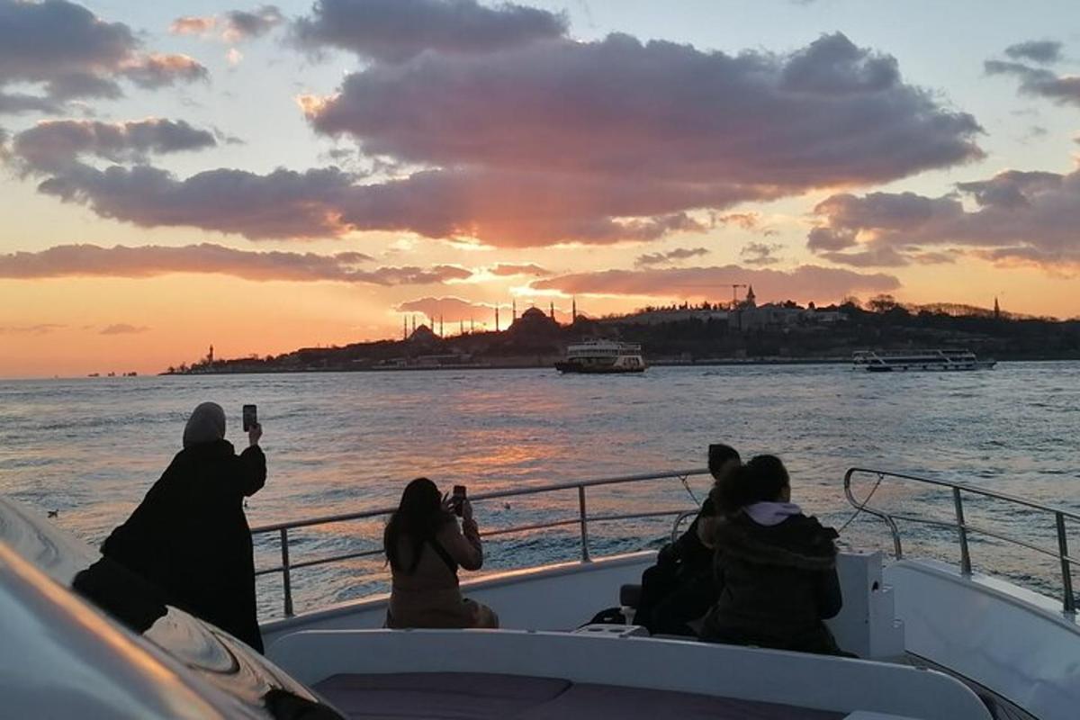 um grupo de pessoas tirando fotos do pôr do sol em um barco