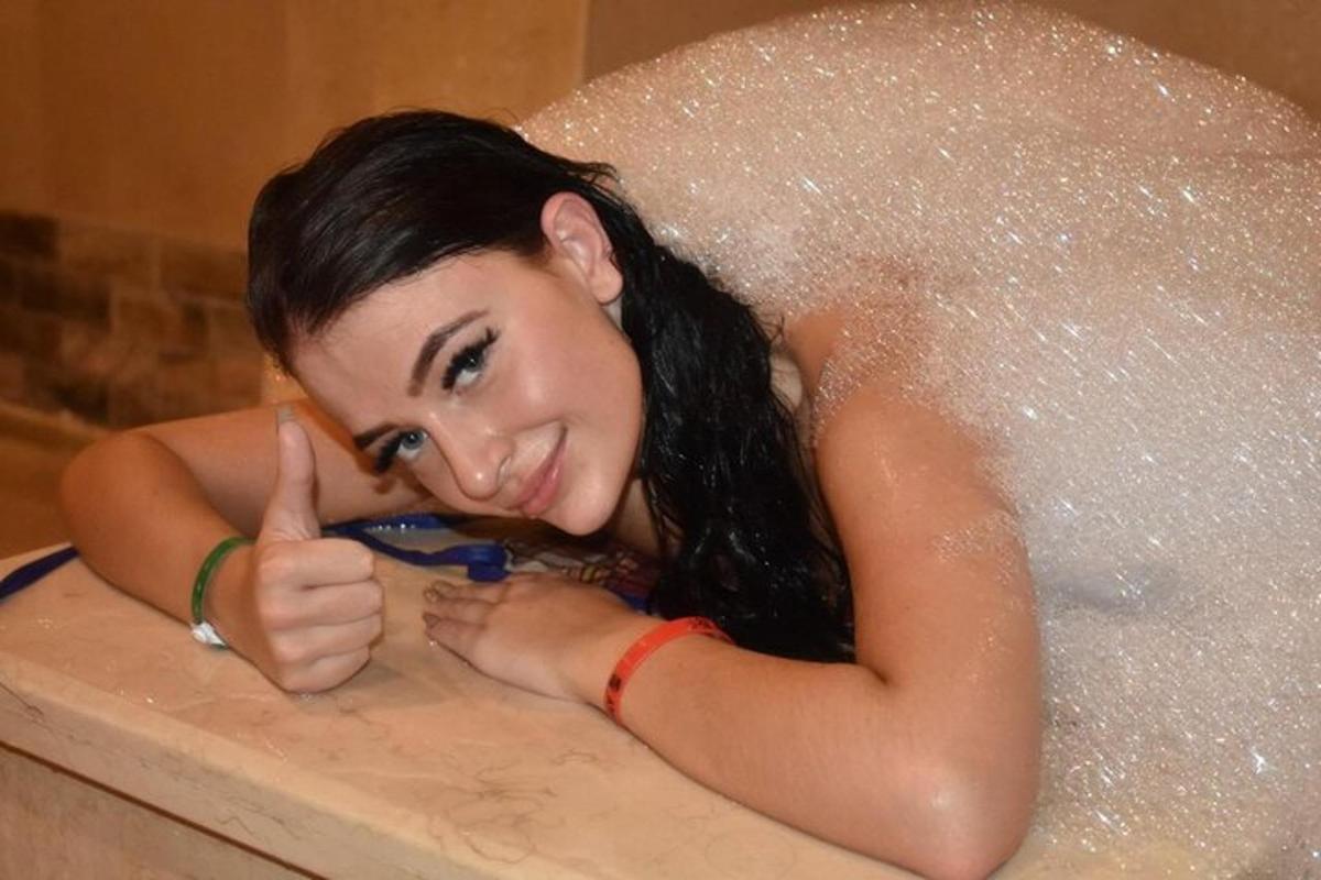Una mujer en una bañera haciendo un gesto de aprobación con el pulgar hacia arriba