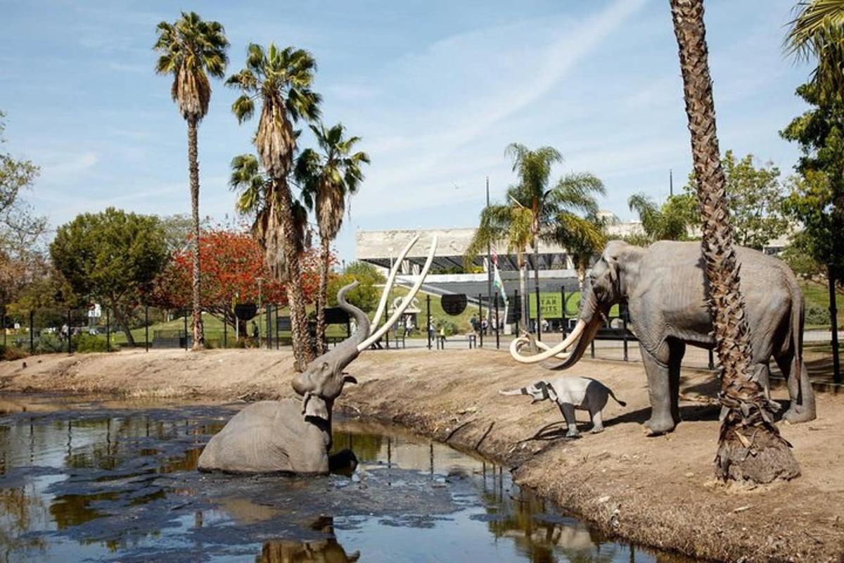 a dog standing next to a statue of an elephant and palm trees