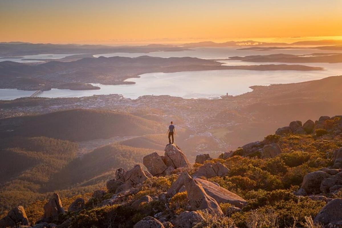 un uomo in piedi sulla cima di una montagna al tramonto