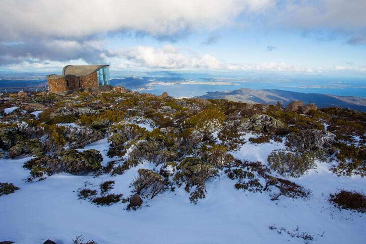 un piccolo edificio in cima a una montagna coperta di neve