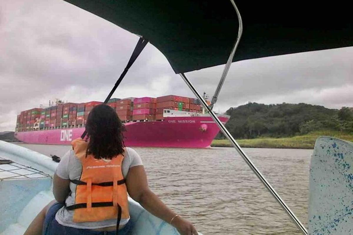 een vrouw op een boot met een containerschip in het water