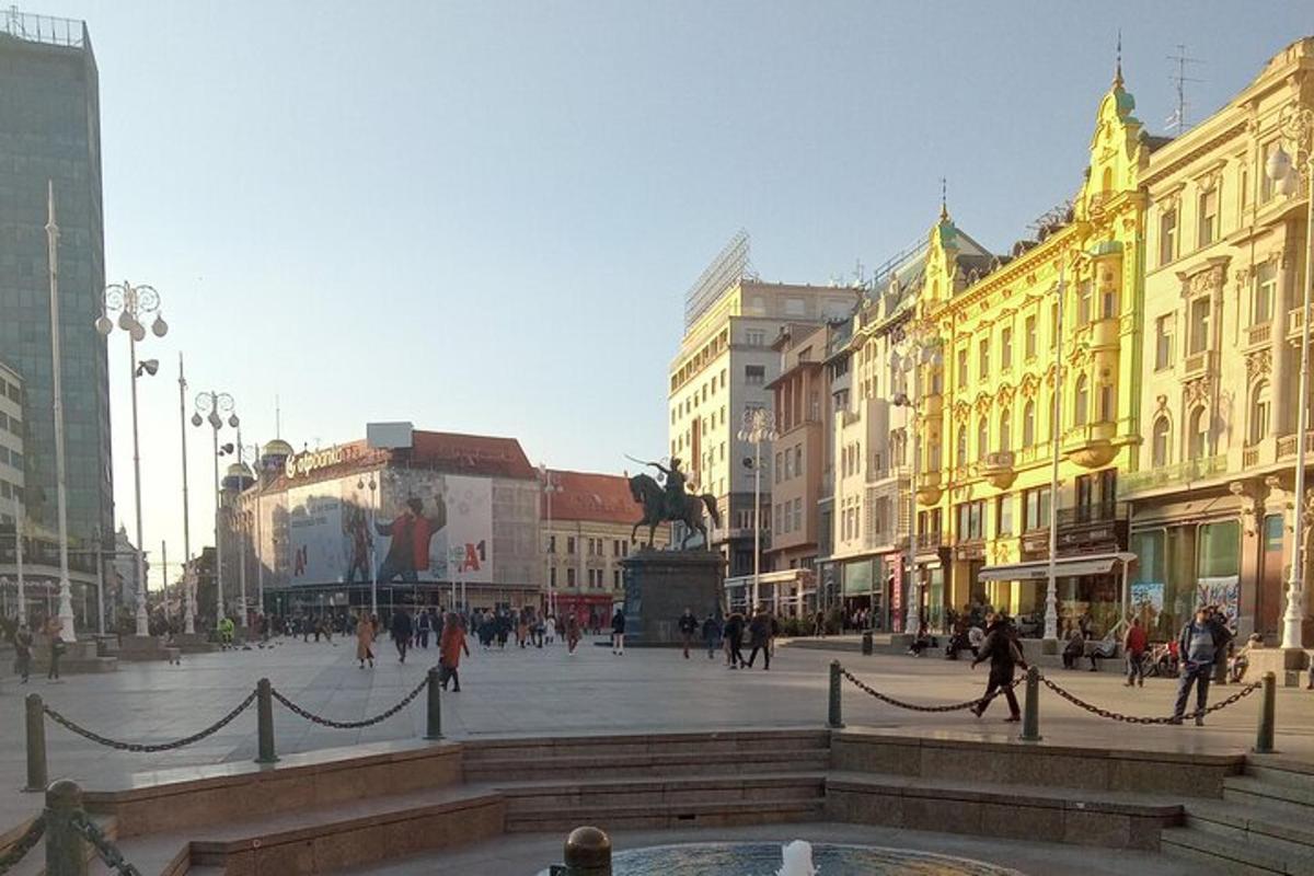 a city square with people walking and a fountain