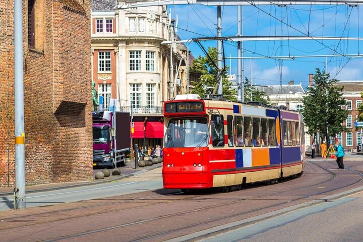 un tramvia vermell, blanc i blau en un carrer de la ciutat