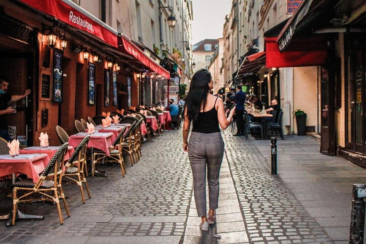 a woman walking down a street with tables and chairs