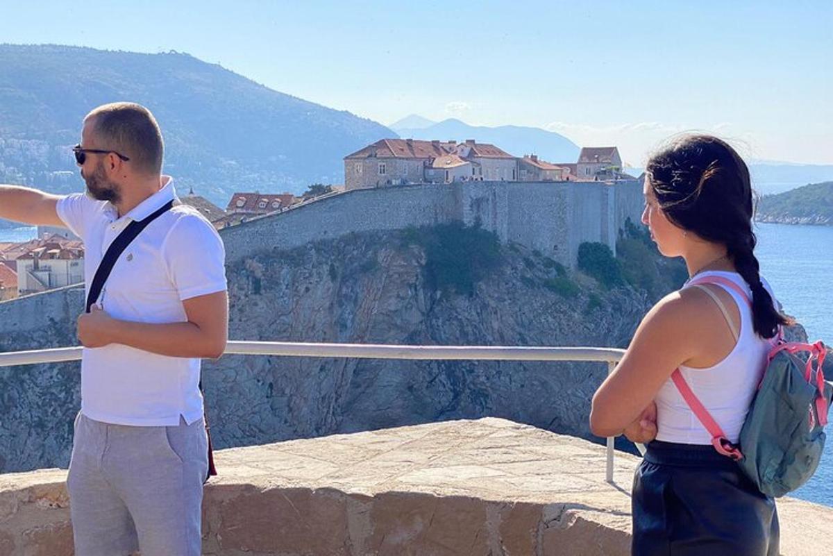 muž a žena stojící na římse a dívající se na hrad