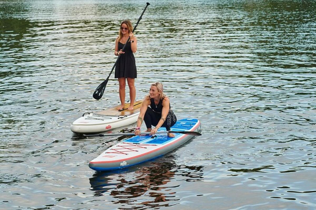 Dvě ženy stojí na paddleboardech ve vodě