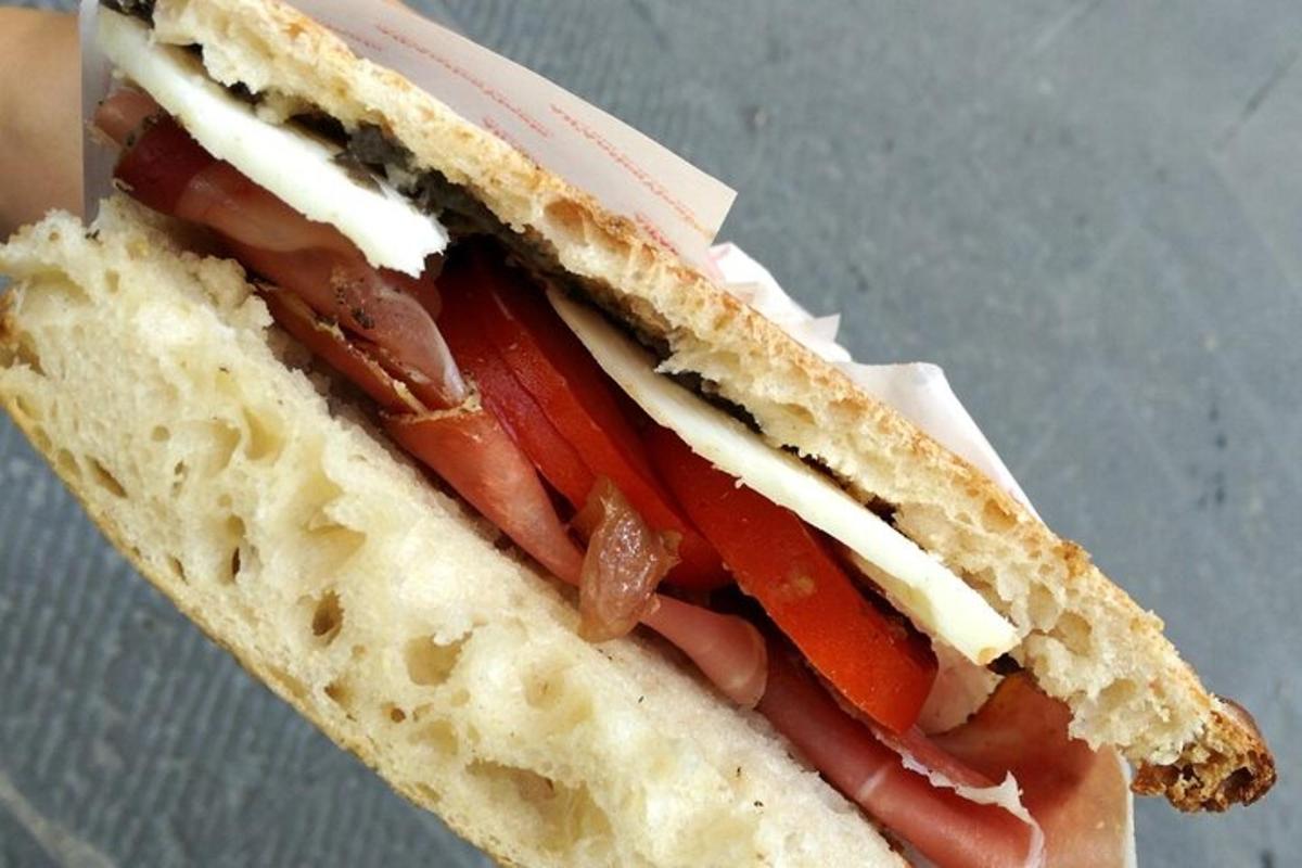 en pølse i et brød med ost og tomater