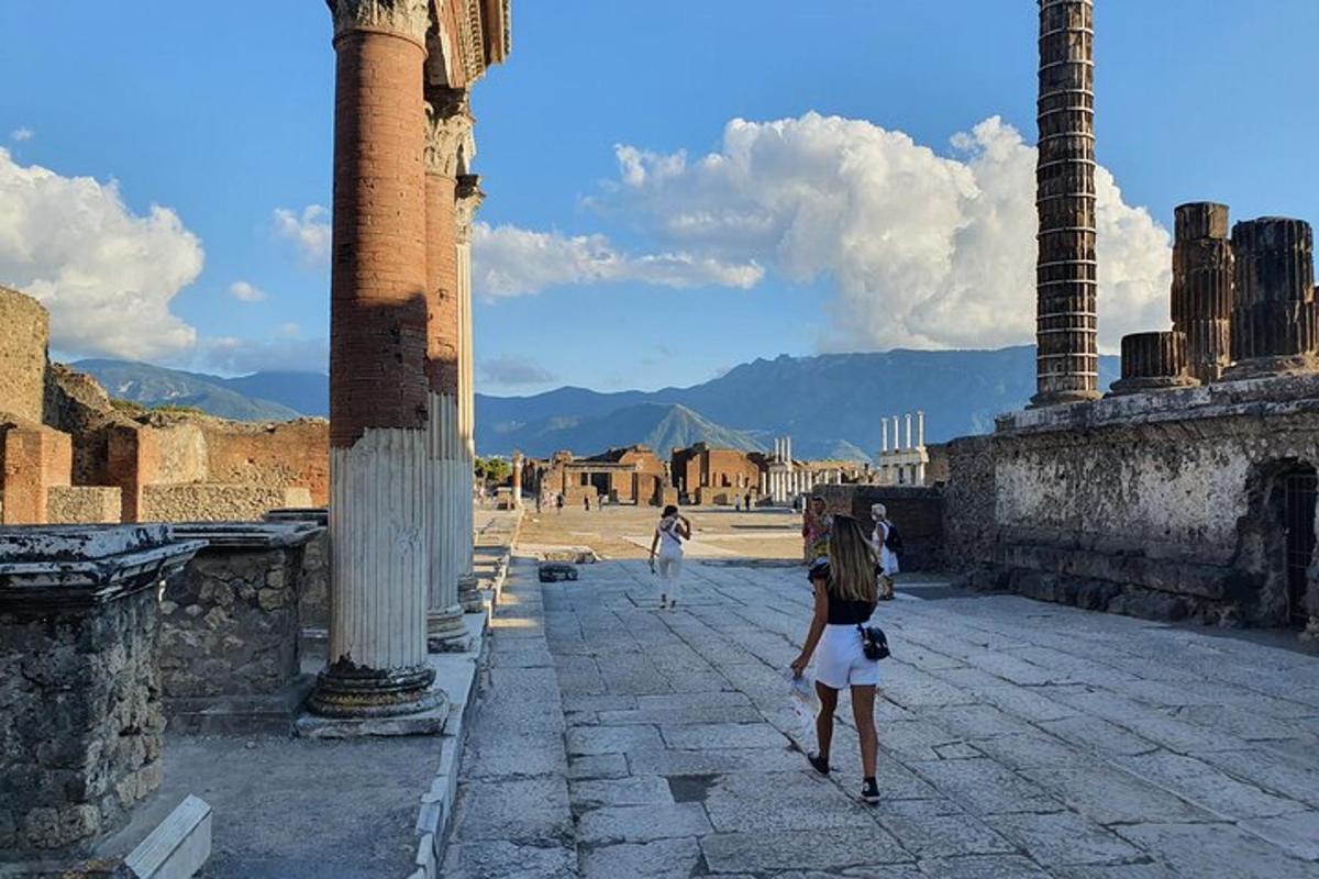 a woman walking through an ancient city with two columns
