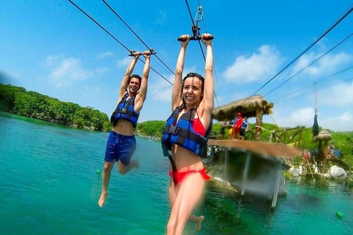 two people are jumping in the water on a zip line