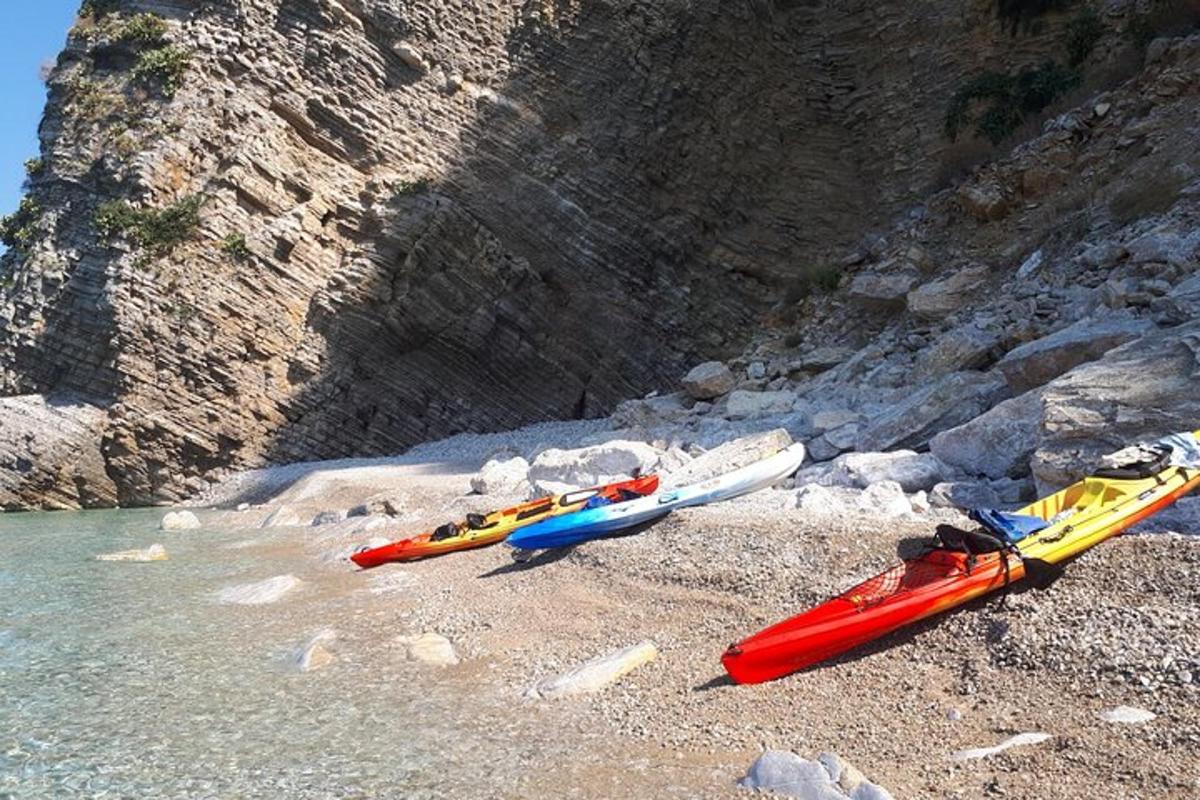 trei caiace pe o plajă stâncoasă lângă apă