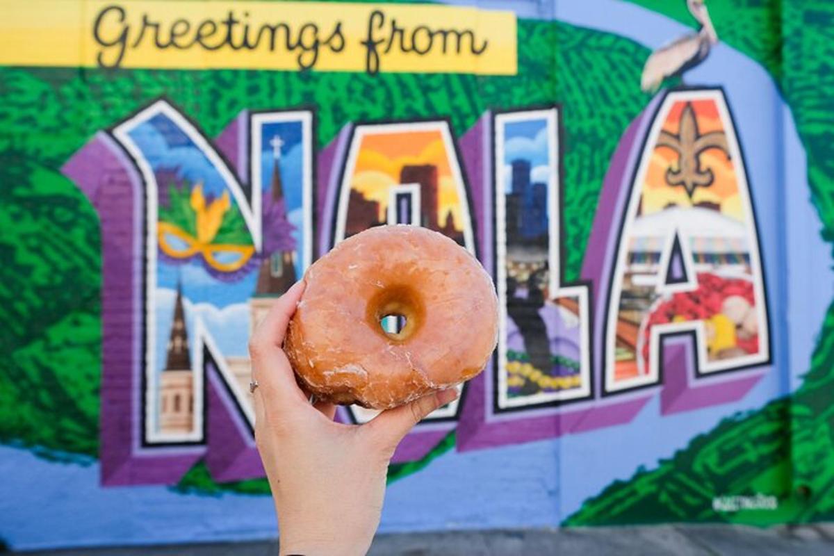 a person holding a donut in front of a sign