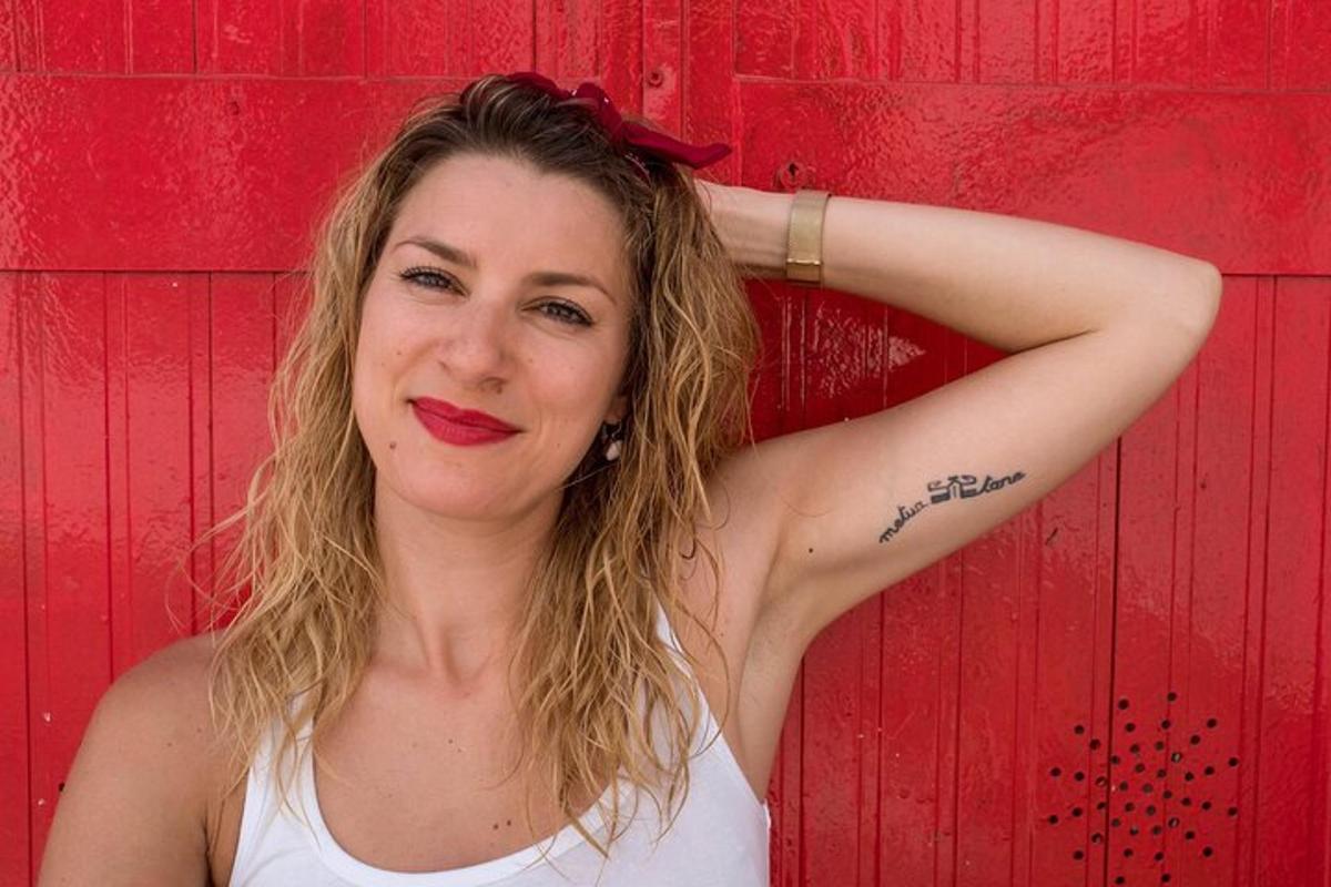 žena s tetováním na paži na pozadí červené zdi