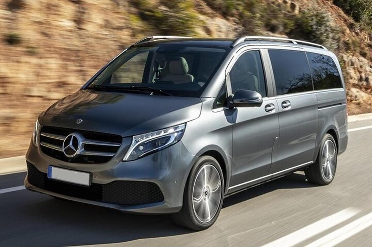 un minivan Mercedes-Benz argintiu care conduce pe un drum