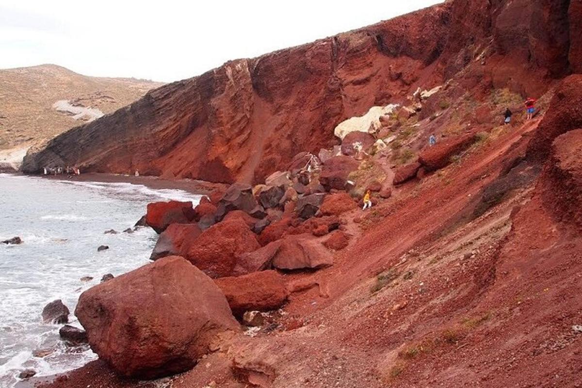 skupina lidí kráčejících po skalnatém kopci u oceánu