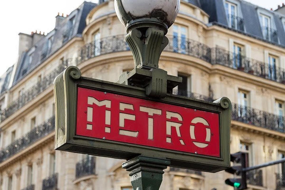 egy metrótábla egy utcai lámpán egy épület előtt