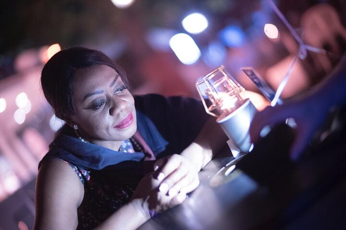 Una mujer sentada en un bar sosteniendo una bebida
