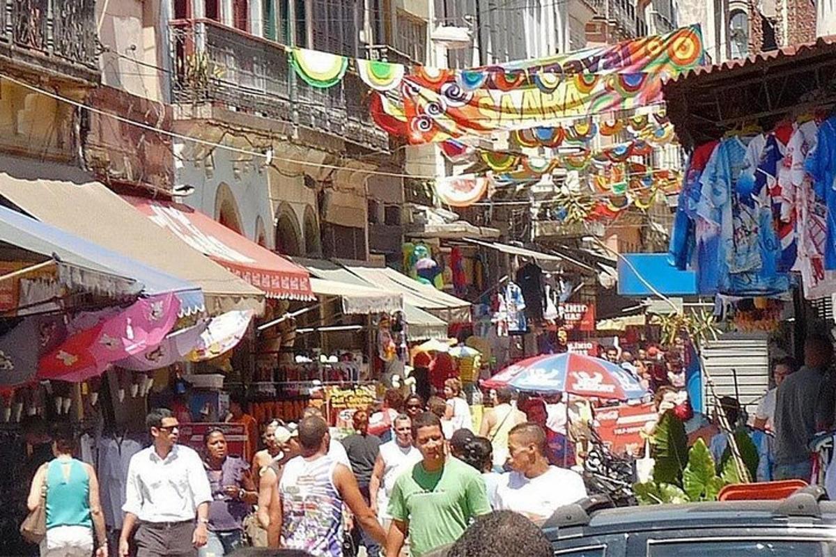 a crowd of people walking through a market with umbrellas