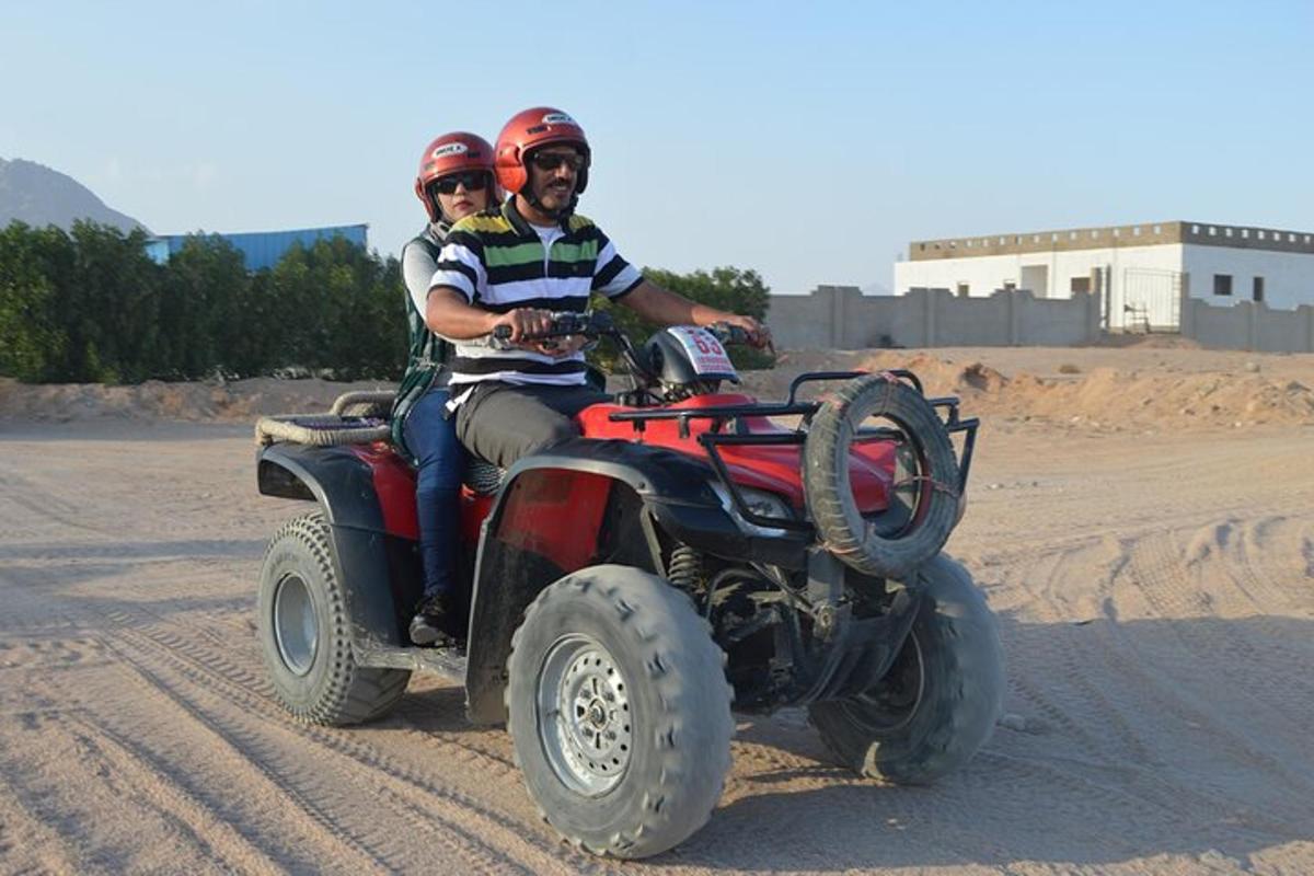 due persone a bordo di un veicolo a quattro ruote nel deserto