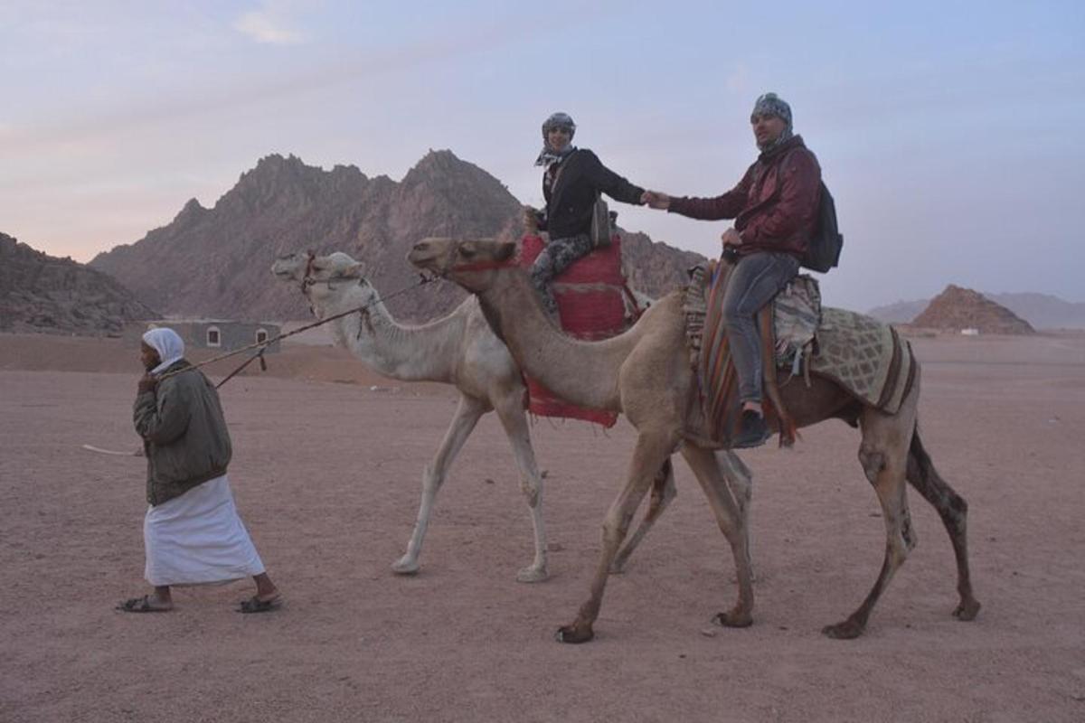 due uomini a cavallo dei cammelli nel deserto