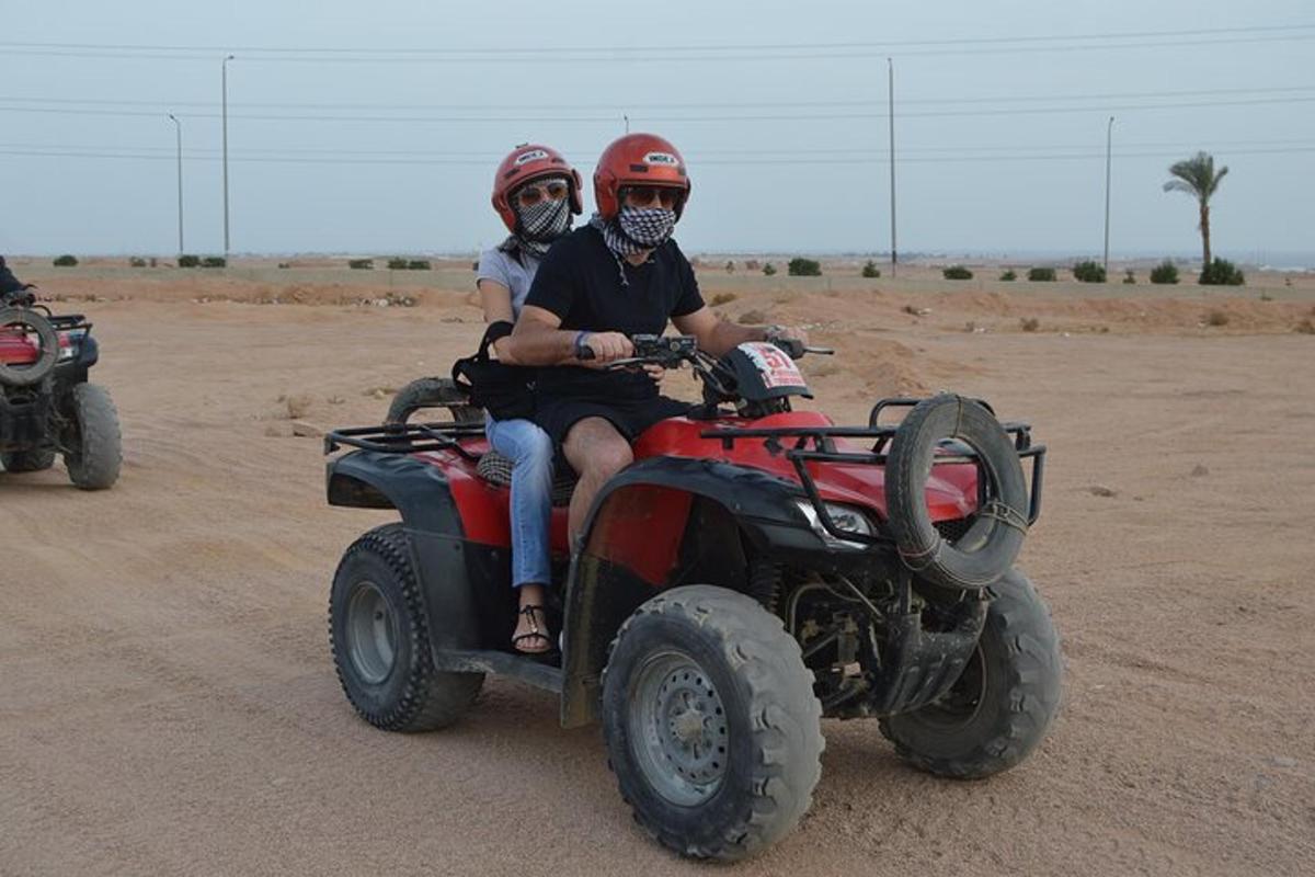 due persone a bordo di un veicolo a quattro ruote nel deserto