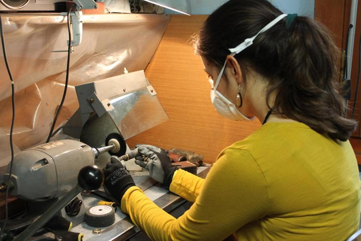 a woman wearing a mask operates a sewing machine